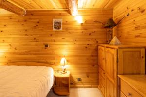 1 dormitorio con 1 cama en una pared de madera en Chalet D'alpage Authentique, en Queige