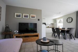 a living room with a television and a table with chairs at Kustverhuur, Park Schoneveld, Stern 254 in Breskens