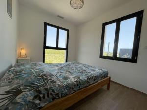 1 dormitorio con 1 cama y 2 ventanas en Tierra Del Viento - Villa Proche de la Mer, en Peyriac-de-Mer