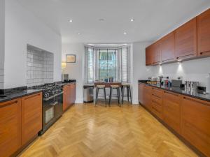 a large kitchen with wooden cabinets and a wooden floor at Pass the Keys Luxury Townhouse In The City in Canterbury