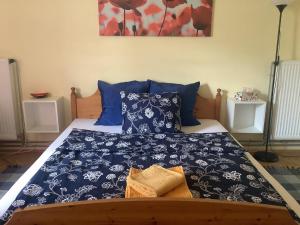 a bed with a blue and white blanket and pillows at Poppy Flower Apartment in Budapest