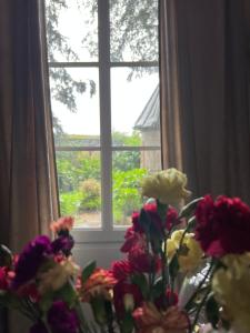 un jarrón de flores sentado frente a una ventana en Le château de cartes des Massés, en Villeneuve-la-Guyard