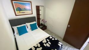 Schlafzimmer mit einem Bett mit blauen und weißen Kissen in der Unterkunft Apartamento central en Armenia in Armenia