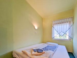 uma pequena cama num quarto com uma janela em Lepke Apartman em Harkány