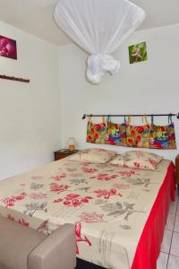 um quarto com uma cama grande e uma colcha vermelha e branca em Logement entier au soleil couchant em Deshaies