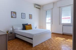 a white bedroom with a bed and two windows at Darsena Luminous & Cozy Apartment in Ferrara