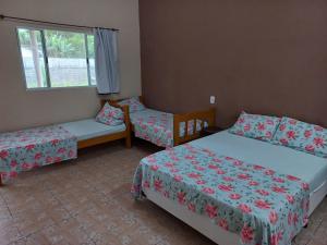 a room with two beds and two chairs and a window at Locação p final de semana Mourada Térrea in Caraguatatuba