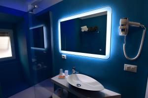 bagno blu con lavandino e specchio di Hotel Fiume a Genova