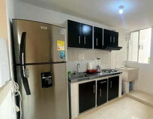 uma cozinha com um frigorífico de aço inoxidável e armários pretos em ST Apto lindo y comodo em Neiva