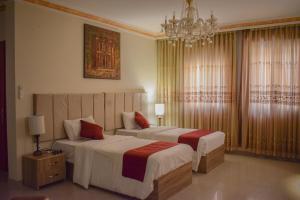 a hotel room with two beds and a chandelier at Twilight Hotel Petra in Wadi Musa