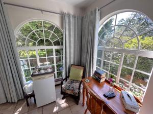 a room with two large windows and a desk and a table at Bancroft B&B in Hilton