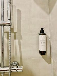 una bottiglia di sapone sul muro di un bagno di Suite San Biagio a Lecce