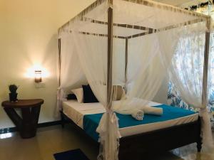 Schlafzimmer mit Himmelbett und weißen Vorhängen in der Unterkunft Elephant Side Bungalow in Udawalawe
