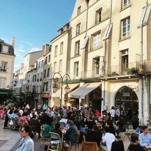 una multitud de personas sentadas en mesas en una calle en Cœur de ville avec parking+gare à proximité de Disney et Paris, en Lagny