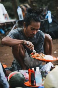 un hombre sentado comiendo un plato de comida en Ila Homestay, en Senaru