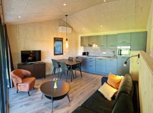 a living room and kitchen with a couch and a table at Chalet de Scherpenweide in Leur