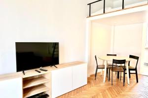ein Wohnzimmer mit einem TV und einem Tisch mit Stühlen in der Unterkunft Design apartment ideal for seaside holidays LIVE IN DR FABRE in Juan-les-Pins