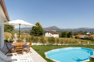 un patio con mesa y sillas junto a una piscina en Refugio das Vinhas en Celorico de Basto