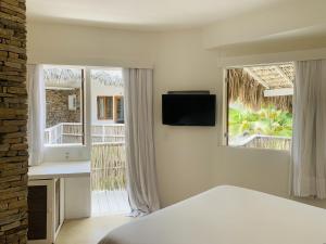 a bedroom with a bed and a tv and two windows at Villa Jericoacoara - La Villa Group in Jericoacoara