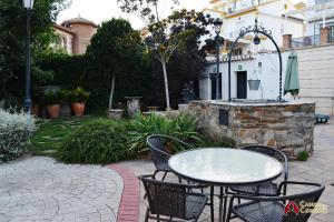 patio con mesa, sillas y chimenea de piedra en APARTAMENTOS CASERIA DE COMARES en Granada