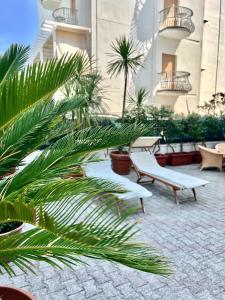 a courtyard with benches and palm trees in a building at Hotel B&B Montecarlo in Milano Marittima