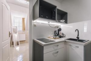 a white kitchen with a sink and a microwave at Apartmanház Soho in Győr