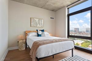 a bedroom with a bed and a large window at NEW apts near Union Park w full amenities - Cloud9-1044 in Chicago