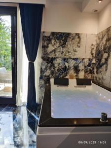 bañera en una habitación con pared de mármol en Studio avec jaccuzzi en Saintry-sur-Seine