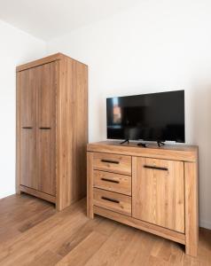 a wooden entertainment center with a flat screen tv on top at HoHome Comfy Apartments in Warsaw