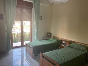 una camera con due letti verdi e una finestra di ST APARTMENT - DI FRONTE AL TRIBUNALE di Nocera a Nocera Inferiore