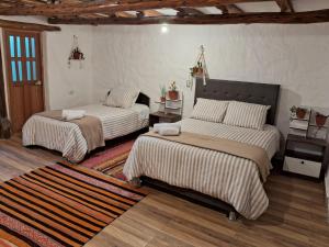 a bedroom with two beds and a rug at KOSKO Casa Hotel in Cusco