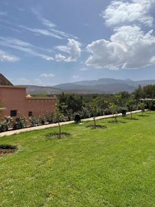 a field of grass with trees and a building at Riad Timskrine in Marrakech