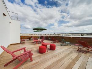 una terrazza con sedie, tavoli e ombrellone verde di Hife Paris Gentilly a Gentilly