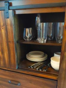a cabinet with plates and wine glasses and utensils at Lazy Bear Cabin 6 - Sleeps Up To 4 
