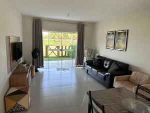 a living room with a couch and a tv at Apt no Cond. Resort Villa das Águas in Atalaia