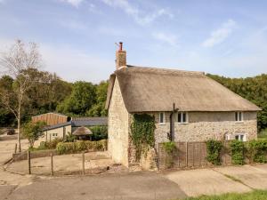 an old stone house with a thatched roof at Dairy Cottage in Weymouth