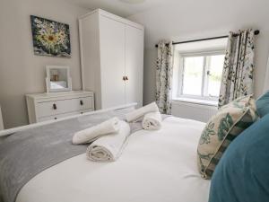 a bedroom with a white bed with towels on it at Dairy Cottage in Weymouth