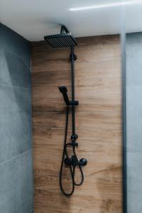 a shower in a bathroom with a wooden wall at Modern Lux Apartment 2 in Brčko