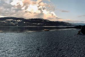 a person sitting on a beach next to a body of water at Petit appartement T2 30m2 in Aix-les-Bains