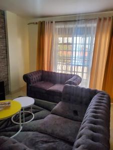 - un salon avec un canapé et une table dans l'établissement J'Melot Adobas Apartment, à Kisumu