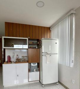 a kitchen with a white refrigerator and wooden cabinets at Apto Luxo completo 3 quartos em Guriri 300 mts da praia Wi-fi grátis in Guriri