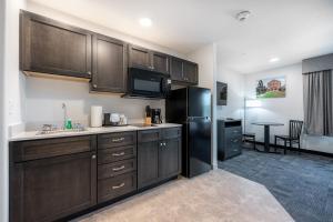 a kitchen with brown cabinets and a black refrigerator at Independence Stay Hotel and Long term suites in Houghton
