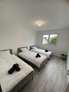 three beds in a room with white walls and a window at Maison moderne in Is-sur-Tille