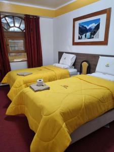 um quarto de hotel com duas camas com cobertores amarelos em Hotel Valery II em Huaraz