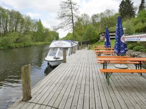 a dock with benches and umbrellas and a boat at Ferienhaus Eldeblick direkt am Eldeufer in Parchim in Parchim