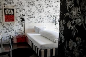 ein Schlafzimmer mit einem weißen Bett mit schwarzweißer Tapete in der Unterkunft Romantikhotel Rebstock art & design in Kehl am Rhein