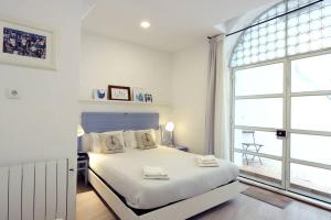 um quarto branco com uma cama e uma grande janela em Alfama Terrace Apartment em Lisboa