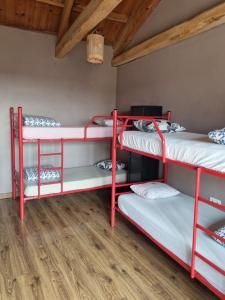 Habitación con 3 literas en una habitación con suelo de madera. en Albergue Gabino, en El Ganso