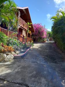 an empty street in front of a house with pink flowers at Le Neem in Saint-François