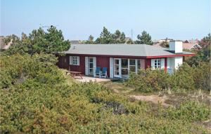 ein kleines rotes Haus auf einem Hügel mit Büschen in der Unterkunft Stunning Home In Hvide Sande With Kitchen in Nørre Lyngvig